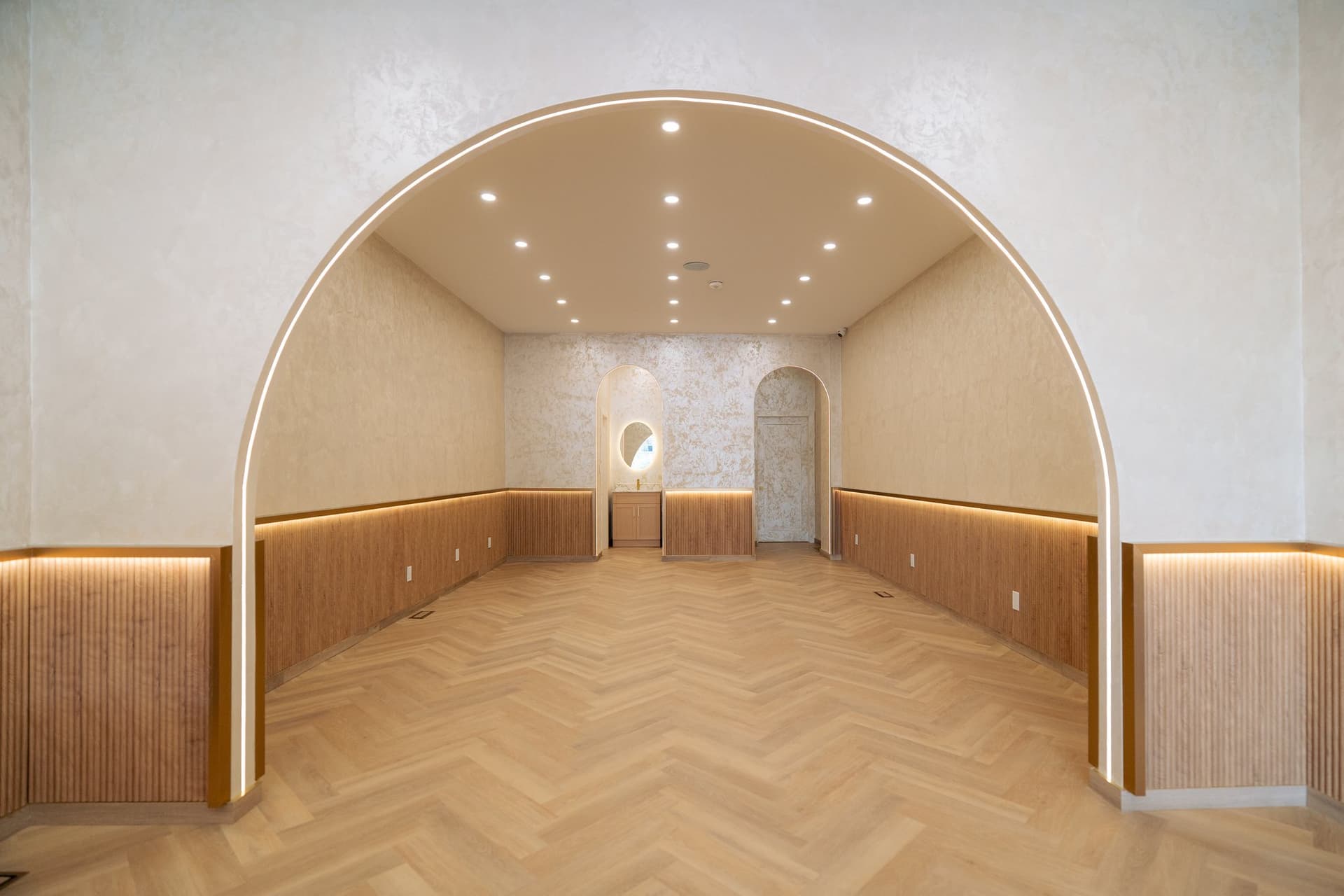 A plastered barrel arch over a cove-lit reeded oak wainscot