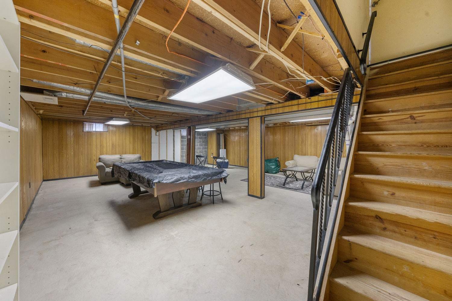 An unfinished basement with exposed joists and a bare concrete floor