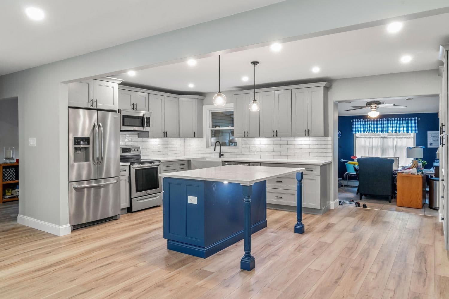 A finished kitchen with shaker cabinetry, an island, and plank flooring running through to the dining room