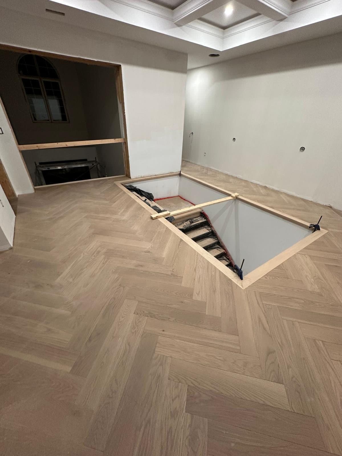 A new stair opening framed and trimmed into a finished herringbone floor