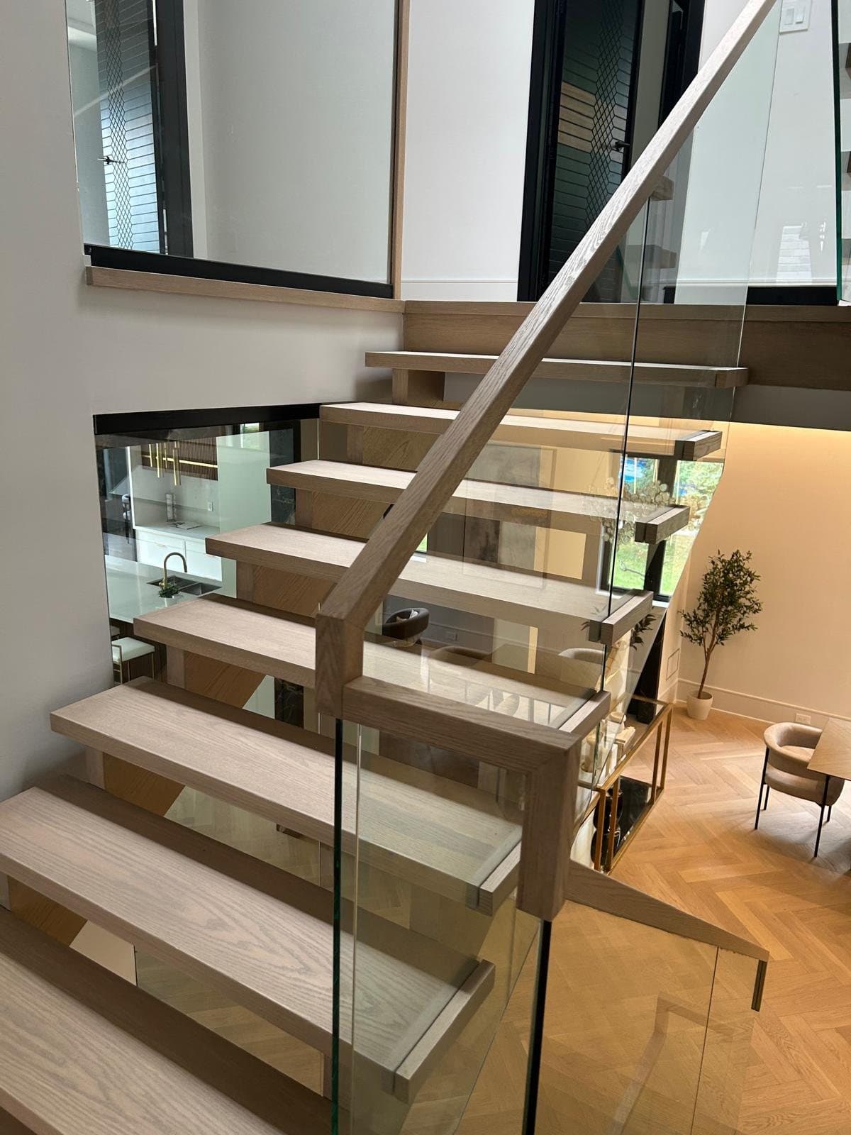 Open-riser white oak staircase with a frameless glass balustrade